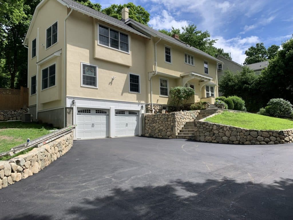 Yellow house with a two-car garage addition and fieldstone retaining walls