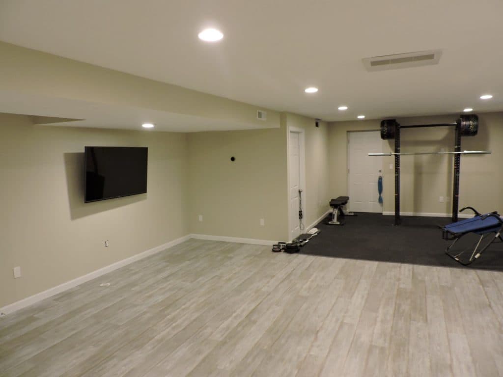 Finished basement home gym with wood-look floor and wall-mounted TV