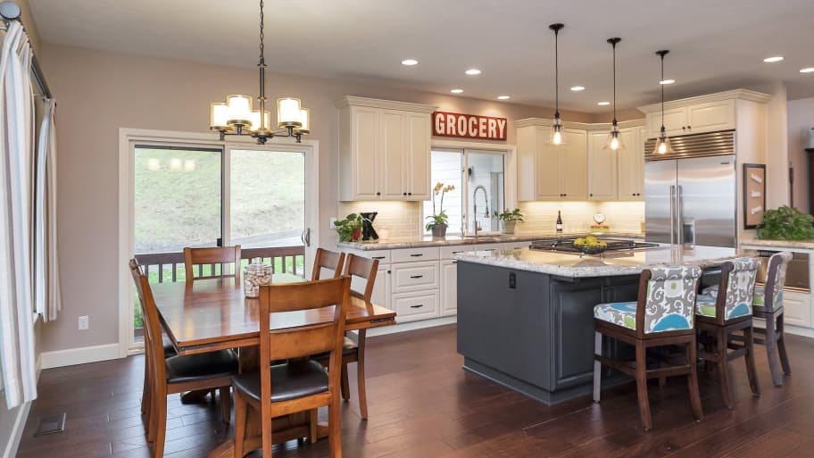 Open kitchen with gray island next to a dining table and chandelier